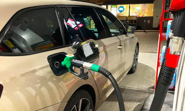 Tankowanie samochodu, zielony pistolet paliwa wlewa się do baku. Obawy o złej jakości paliwo diesel objawy mogą pojawić się po takiej wizycie na stacji.