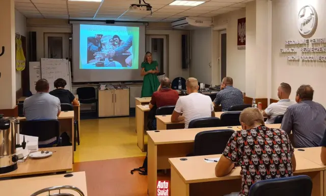 Szkolenie z zbijania punktów karnych. Wykładowczyni omawia rozwój choroby alkoholowej, a uczestnicy słuchają.