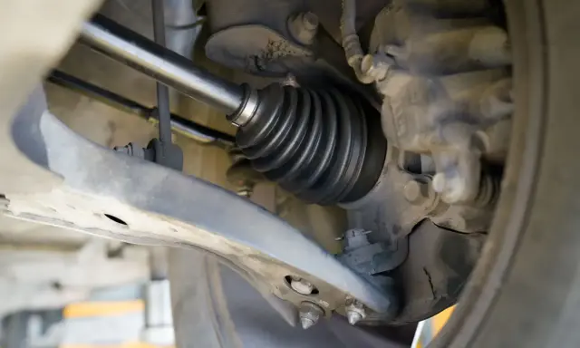 Szczegółowy widok mechanizmu napędowego, pokazujący osłonę przegubu. To kluczowy etap w instrukcji wymiany półosi krok po kroku.