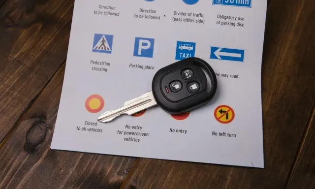 Kluczyk do samochodu na arkuszu z przepisami drogowymi. Chcesz wiedzieć, jak szybko zdać prawo jazdy? Zacznij od nauki znaków!