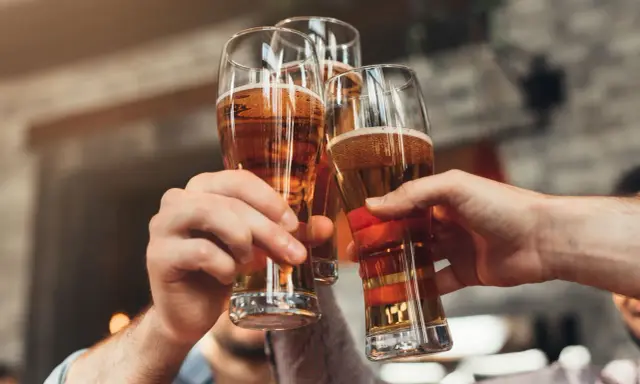Trzy ręce wznoszą kufle z piwem do toastu. Zastanawiasz się, ile to piw, gdy masz 0,2 promila?