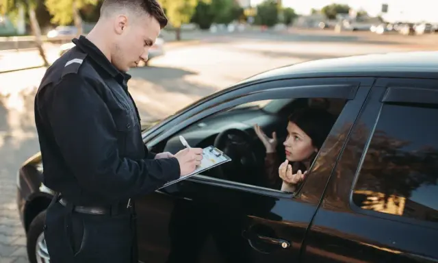 Policjant spisuje mandat, a kierowca tłumaczy, za co zabierają prawo jazdy na 3 miesiące.