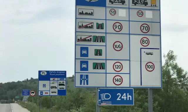 Znaki drogowe informujące o opłatach i limitach prędkości na drodze jednojezdniowej dwukierunkowej.
