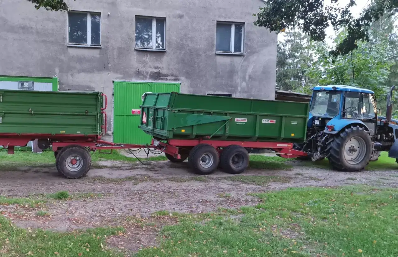 Niebieski traktor z przyczepą rolniczą, gotowy do pracy. Posiadanie prawa jazdy kategorii T to klucz do obsługi takich maszyn.