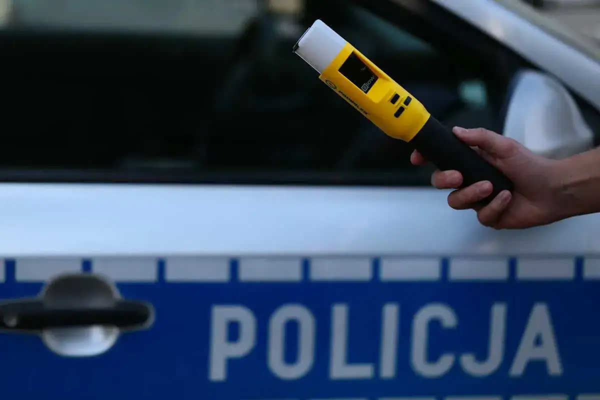 Policjant sprawdza poziom alkoholu we krwi kierowcy przy użyciu alkomatu.