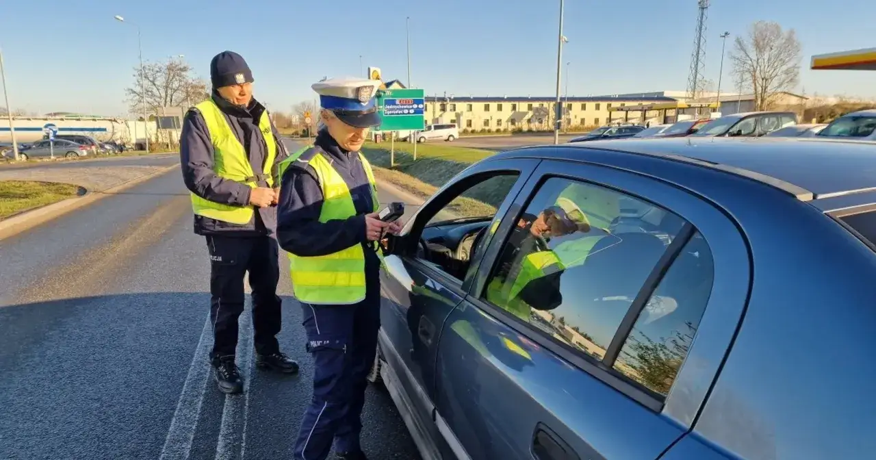 Policjanci kontrolują pojazd, kierowca otrzyma mandat za brak świateł.