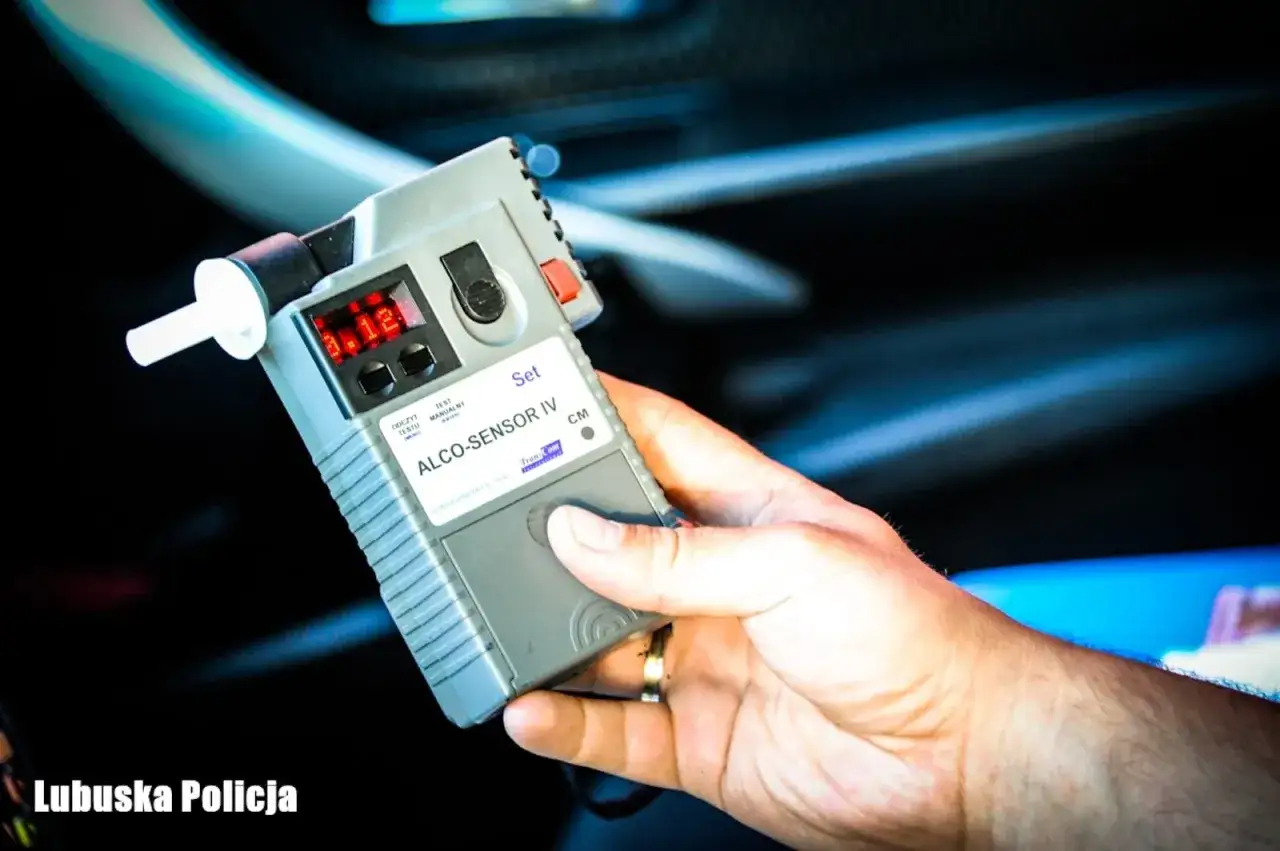 Dłoń trzyma alkomat z wynikiem 0.12 promila. Pamiętaj, że powyżej 0.5 promila jaka kara grozi za jazdę.