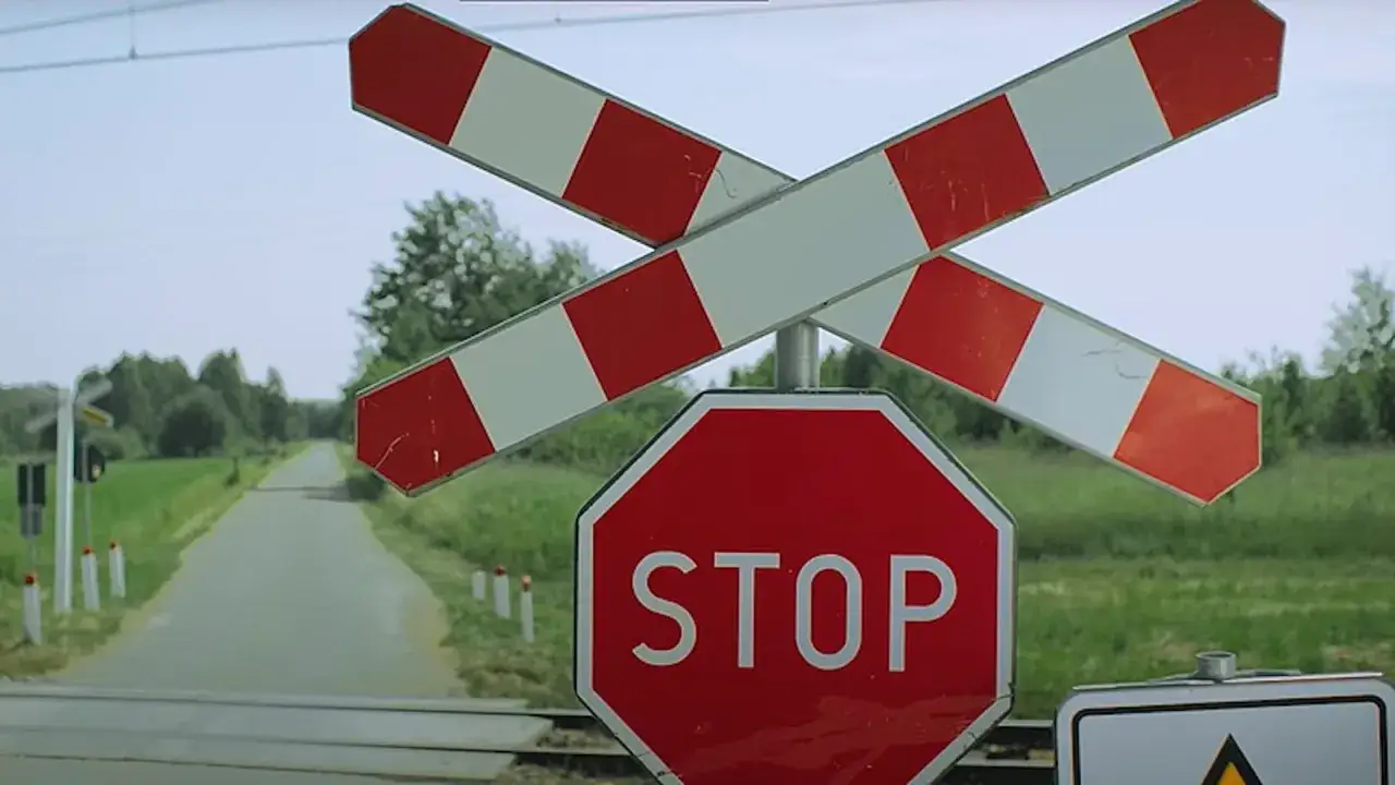 Przejazd kolejowy z zaporami i znakiem STOP. Uważaj, bo art. 92 par. 1 k.w. i punkty karne czekają na nieostrożnych kierowc&oacute;w.