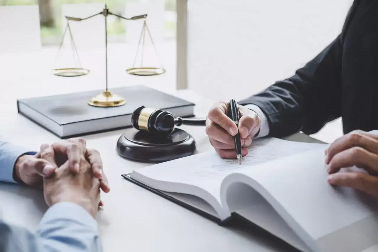 Prawnik pisze dokument, obok waga sprawiedliwości i młotek. Zapewnienie legal protection.