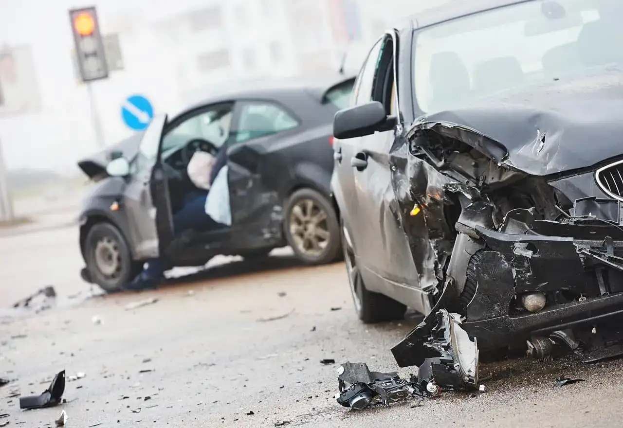 Wypadek drogowy. Uszkodzone samochody, jeden z otwartymi drzwiami i widocznym manekinem. Możliwe odszkodowanie z OC sprawcy za uszczerbek na zdrowiu.