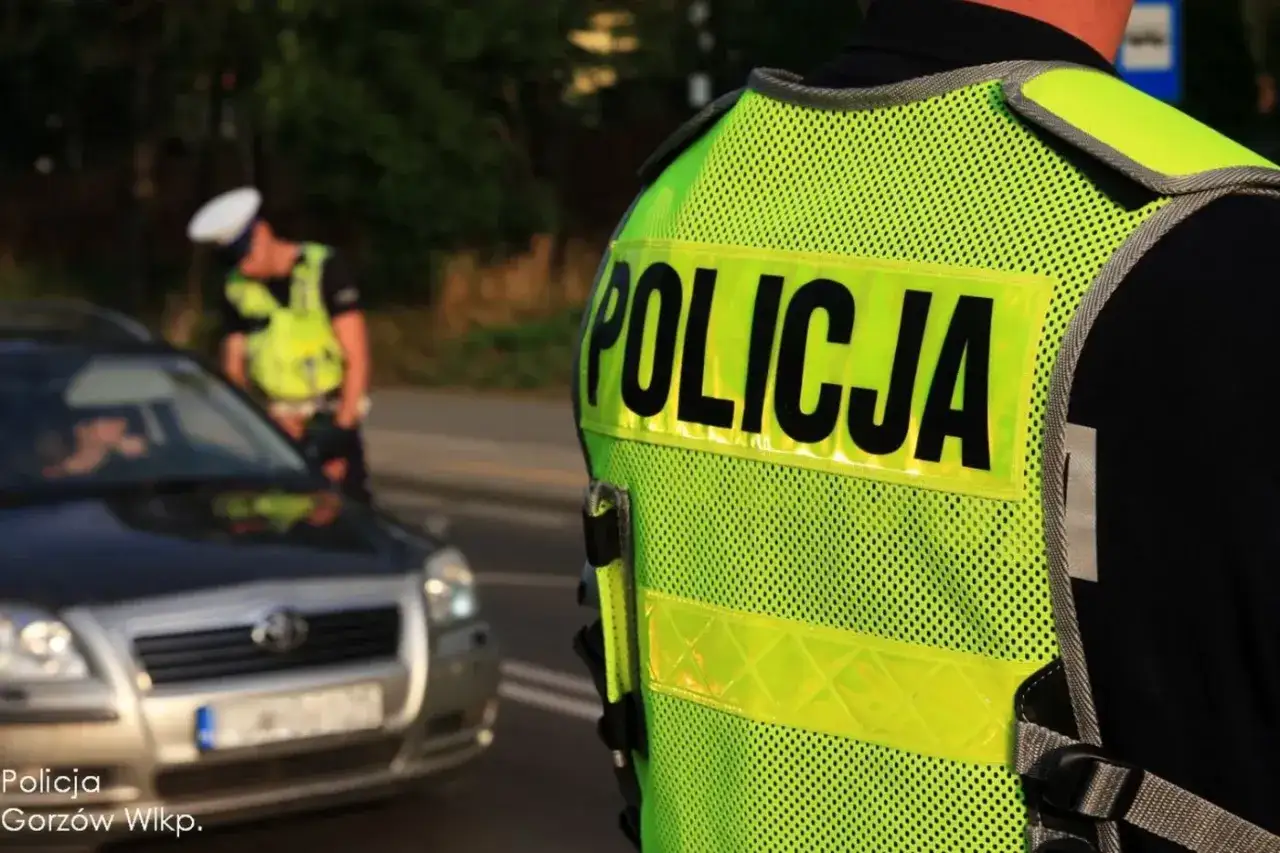 Policjant kontroluje kierowcę, kt&oacute;ry korzystał z telefonu podczas jazdy.
