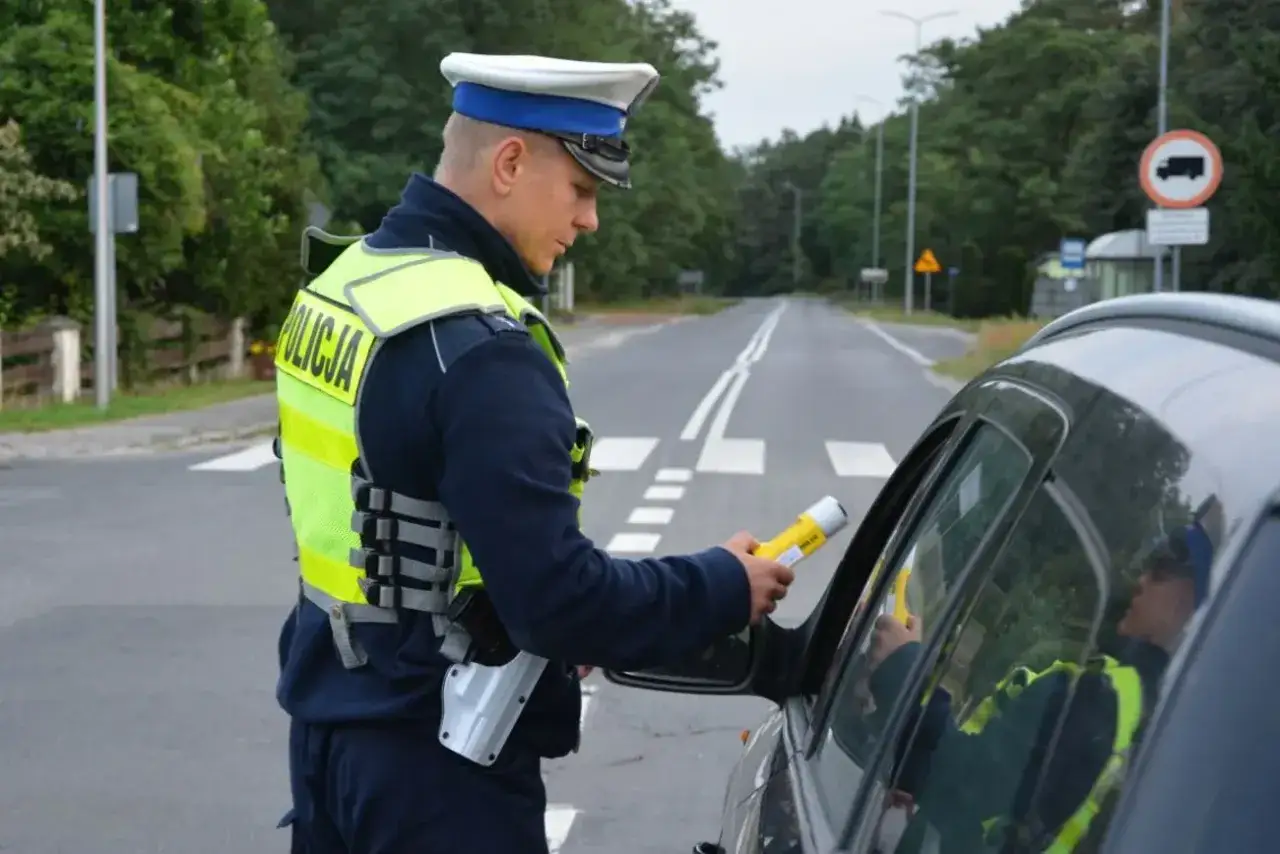 Policjant z alkomatem w ręku kontroluje kierowcę. Wynik badania to 0,17 promila w wydychanym powietrzu.