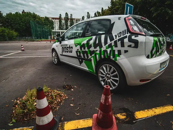 Samochód szkoleniowy z napisem "Prosto" i grafiką "Learn to Drive" na placu manewrowym. Idealne miejsce na jazdy doszkalające odlewnicza.