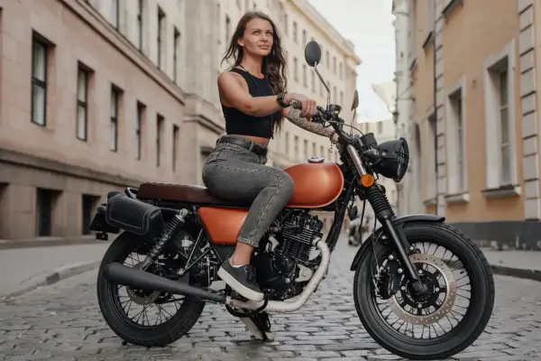 Kobieta na stylowym motocyklu 125cc. Czy na motor 125 trzeba mieć prawo jazdy? To pytanie zadaje sobie wiele osób, które marzą o takiej maszynie.